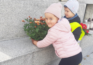 Zuzia i Leoś składają kwiaty na Pomniku Poległych Harcerek i Harcerzy.